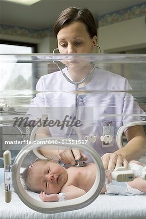 Infirmière examinant un nouveau-né dans un incubateur