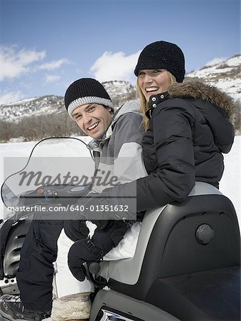 Portrait of a young couple sitting on a snowmobile