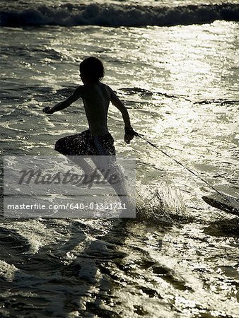 Boy running on beach with boogie board