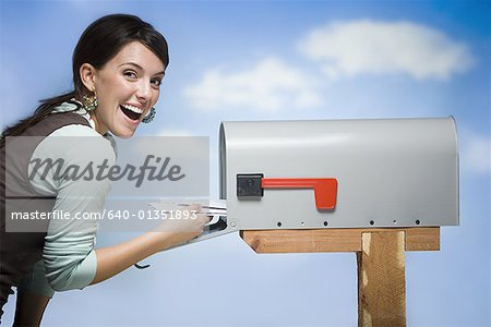 Woman getting mail from letterbox smiling