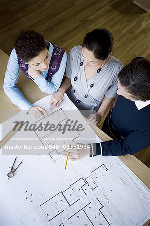 High angle view of three architects looking at blueprints