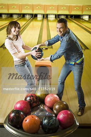 Portrait d'un jeune homme et une jeune adolescente se battre pour une boule de bowling