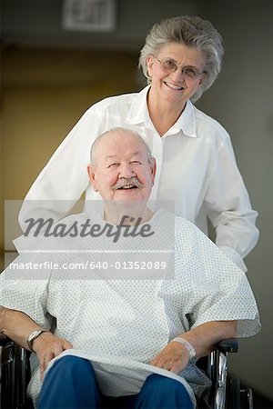 Portrait d'une femme senior aidant un homme senior en fauteuil roulant