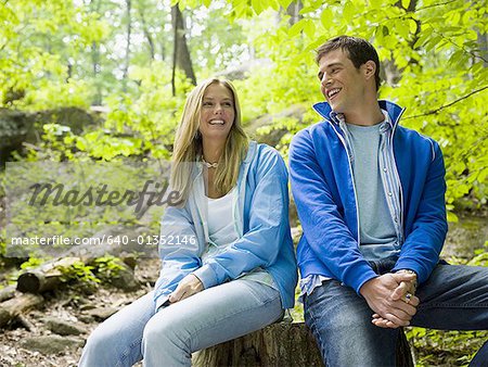 Close-up of a young couple sitting in the forest and smiling