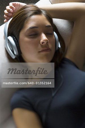 Vue grand angle sur une jeune femme portant un casque d'écoute avec les yeux fermés