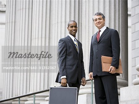 Low angle view of two men smiling and standing in front of a courthouse