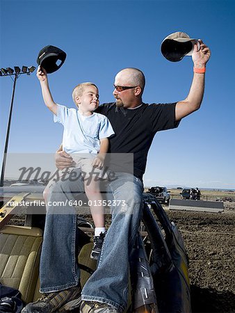 Fils de père et de jeunes agitant des casquettes de base-ball dans l'air