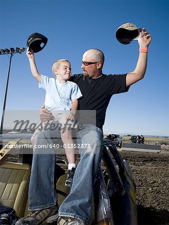 Father and young son waving ball caps in air