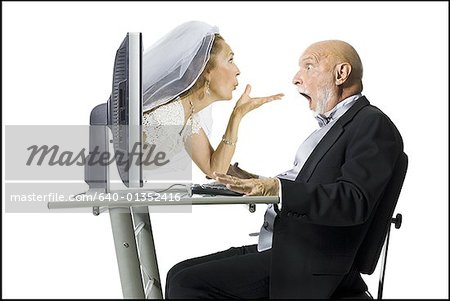 Profile of a senior woman blowing a kiss through a computer monitor to her groom