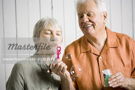 Close-up of an elderly couple blowing bubbles with a bubble wand