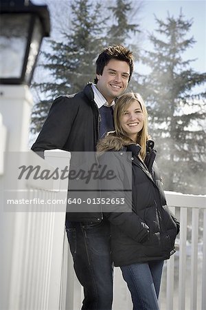 Portrait of a young couple standing beside a fence