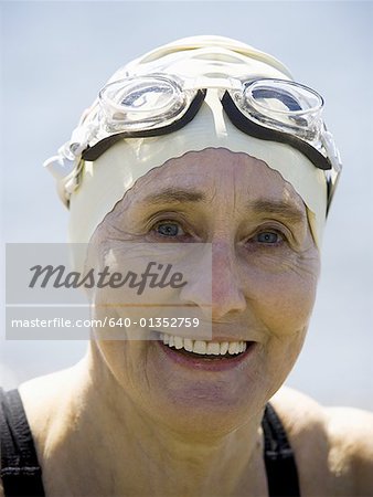 Mature femme avec chapeau et des lunettes souriant de natation