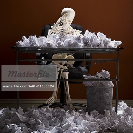 Squelette assis au comptoir avec des papiers froissés