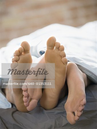 Feet of a couple lying on the bed