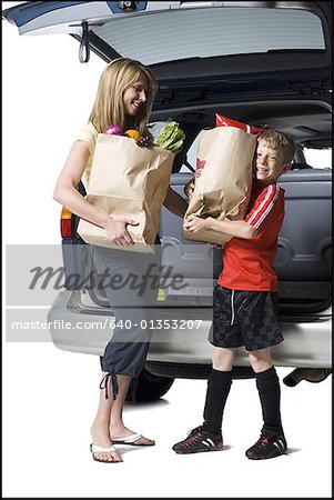 Young son helping mother with groceries