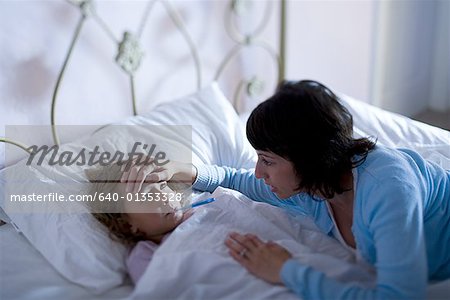High angle view of a mother checking her daughter's temperature