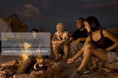 Deux couples assis près d'un feu de camp