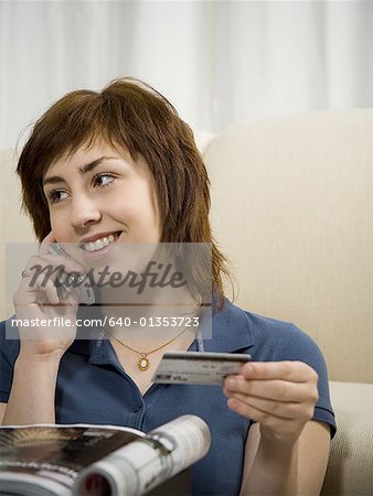 Close-up of a teenage girl talking on a mobile phone and holding a credit card