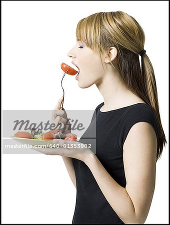Profile of a young woman eating a slice of tomato