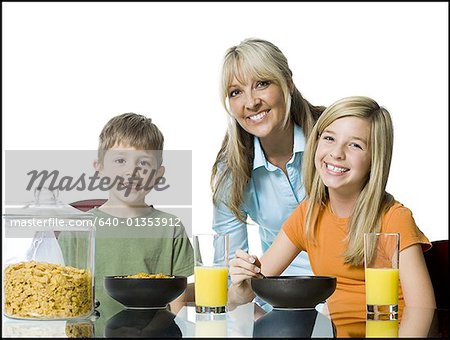 Portrait of a mid adult woman and her two children at the breakfast table