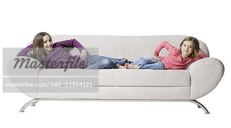 Portrait of two sisters lying on a couch