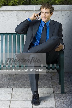 Businessman sitting on a bench, talking on a mobile phone