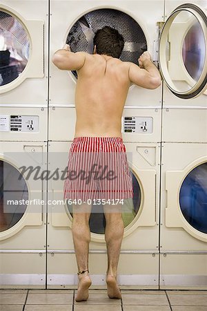 Man in boxers looking in dryer at Laundromat