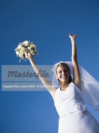 Portrait of a bride holding a bouquet of flowers with her arms raised