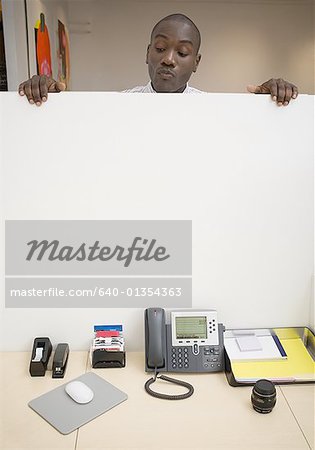 Businessman peeking over cubicle wall