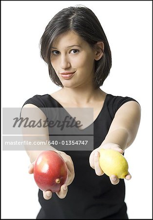 Portrait of a young woman holding a lemon and a mango