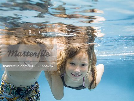 Portrait of two children swimming underwater and smiling