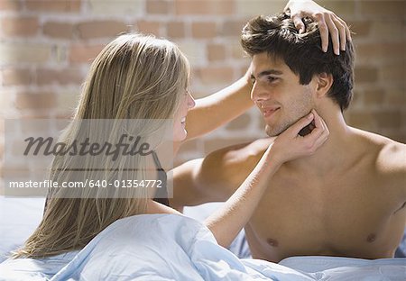 Close-up of young woman and man looking at each other on a bed
