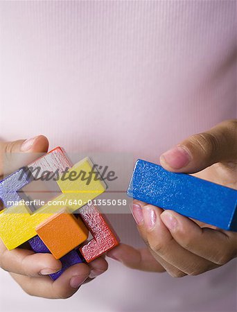 Mid section view of a woman trying to piece together of a cube puzzle