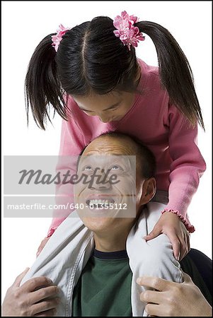 Close-up of a father with his daughter sitting on his shoulders