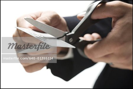 Close-up of a person's hand cutting a credit card with a pair of scissors