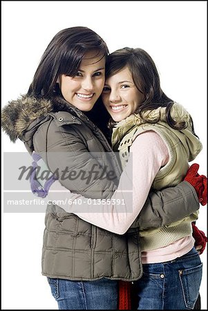 Zwei Frauen umarmten und lächelnd mit Wintermäntel