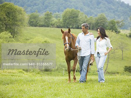 homme et une femme qui marche avec un cheval