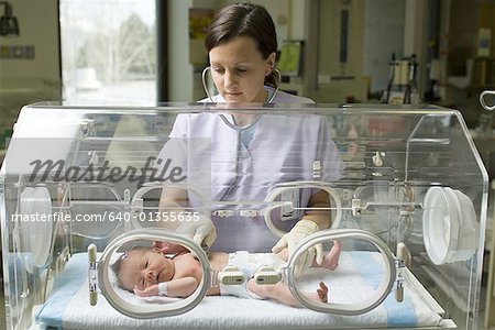 Infirmière examinant un nouveau-né dans un incubateur