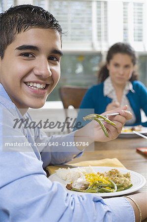 Portrait d'un adolescent assis à une table à manger et souriant