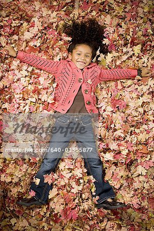 Jeune fille jouant dans les feuilles mortes