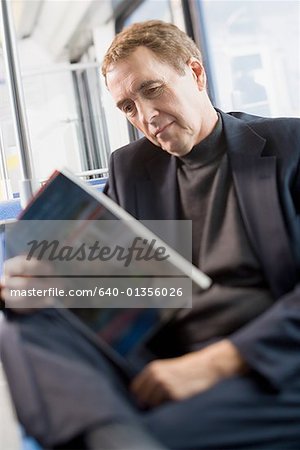 Senior homme lisant un livre sur un train de banlieue