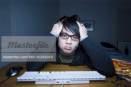 Homme au clavier avec casque et mains sur la tête de moue