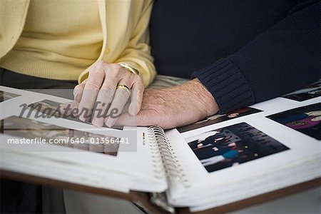 Mid section view of a couple looking at a photo album