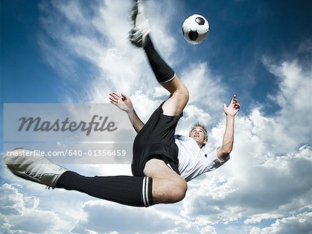 Joueur frappe le ballon pendant que silhouetté sur un ciel bleu nuageux