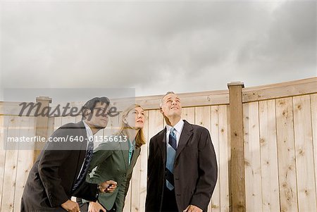 Low angle view of two businessmen and a businesswoman standing looking up