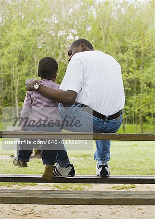 Père et fils assis sur un banc de parc