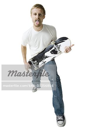 Portrait d'un jeune homme tenant une planche à roulettes comme une guitare