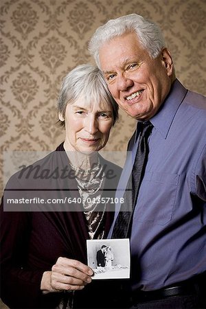 Portrait of an elderly couple showing a photograph