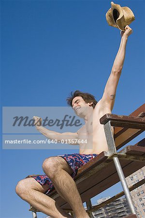 Low angle view of a young man sitting on a lifeguard chair