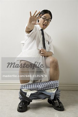 Portrait of a young man sitting on a toilet